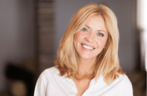 Middle aged woman smiling at the camera at home. 300x197