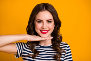 Cute young woman with red lipstick smiling and revealing her perfect smile with porcelain veneers in McLean, VA