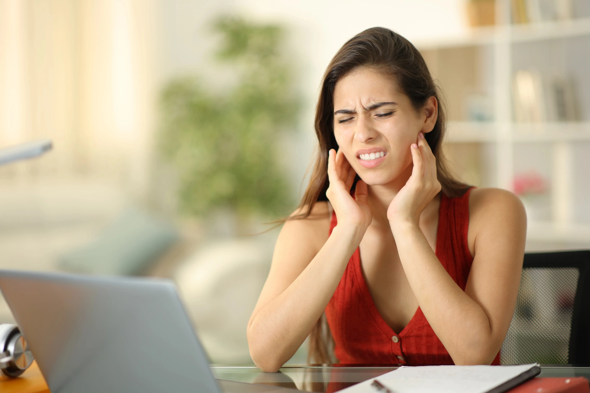 woman holding her jaw in pain due to jaw pain before seeing a TMJ dentist in McLean