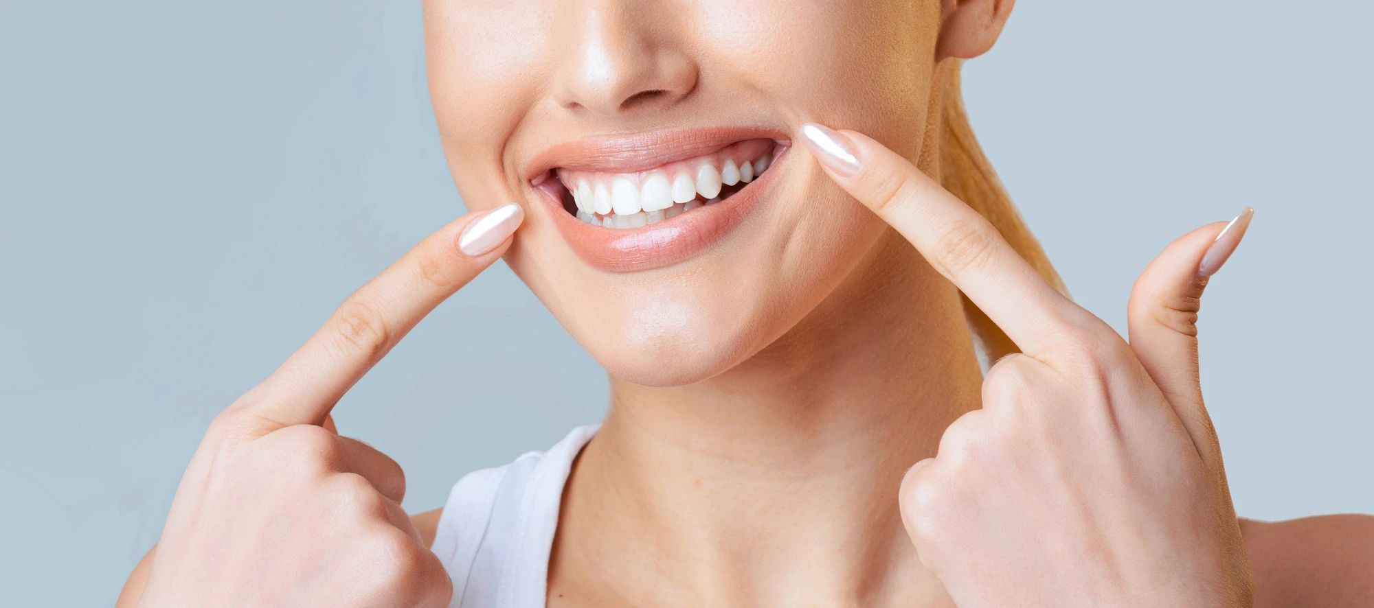 woman pointing at her bright smile cosmetic dentists in Arlington